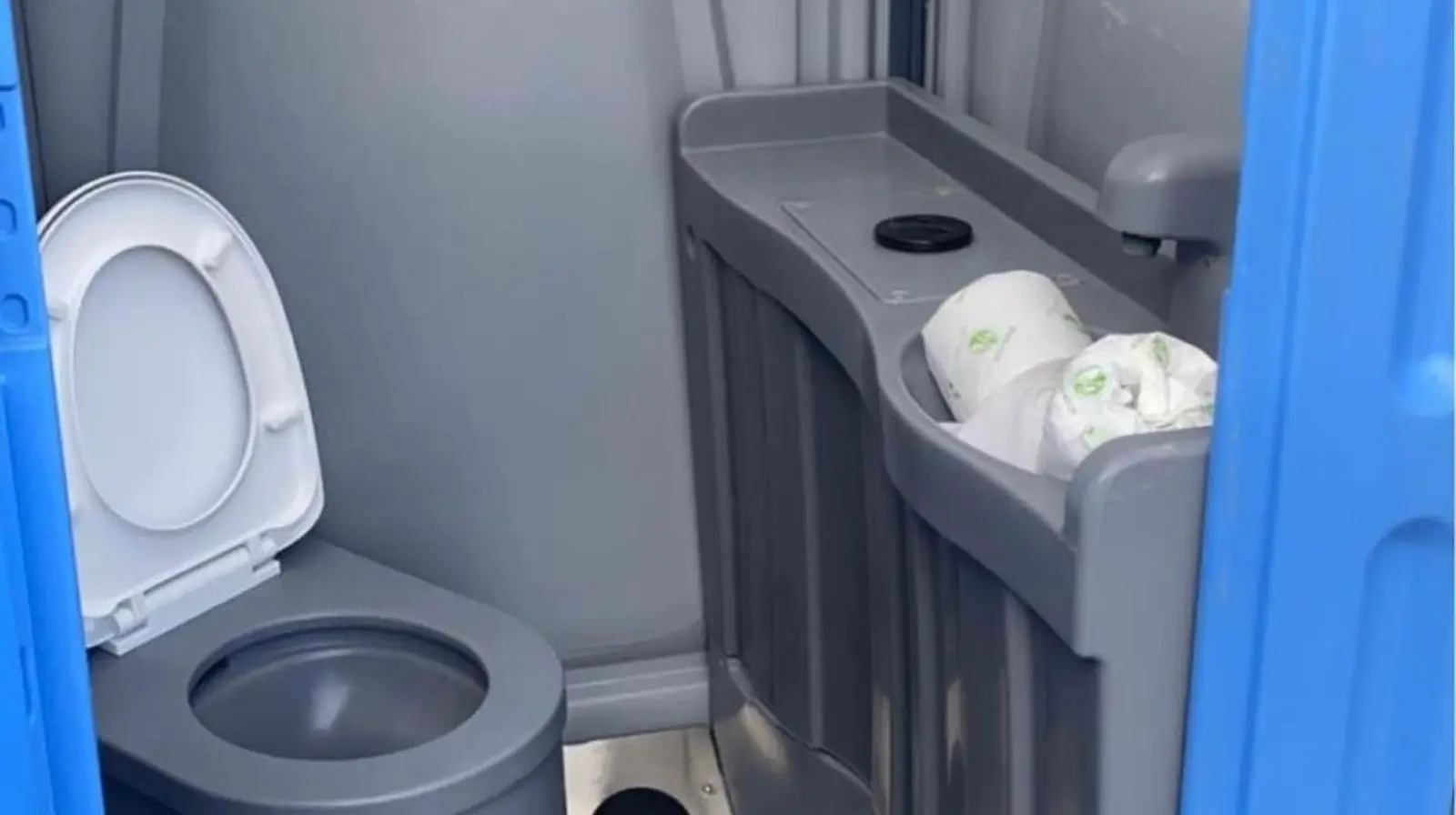 Inside a deluxe flushing portable toilet with a sink and paper towel holder