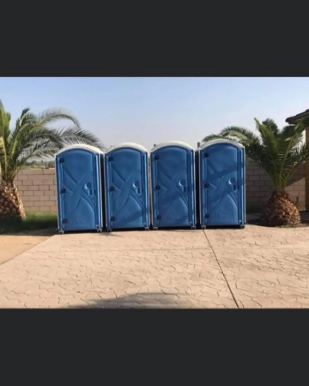 Portable toilets lined up in a row on grass at an outdoor event.