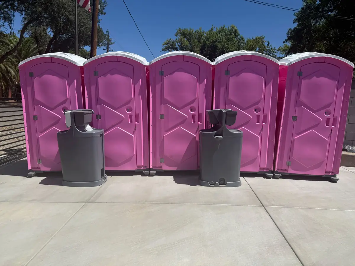 Row of pink portable toilets with hand-wash stations for an event