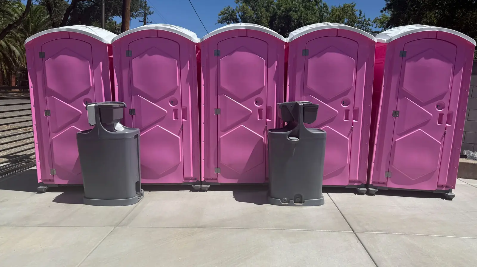 Row of pink portable toilets with two hand-wash stations for an event