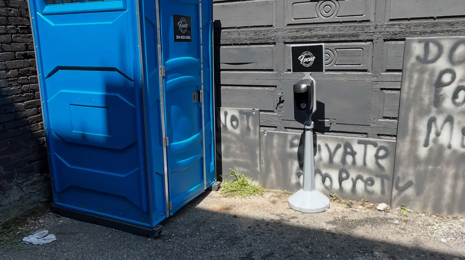 Blue standard porta potty placed on pavement at a work site