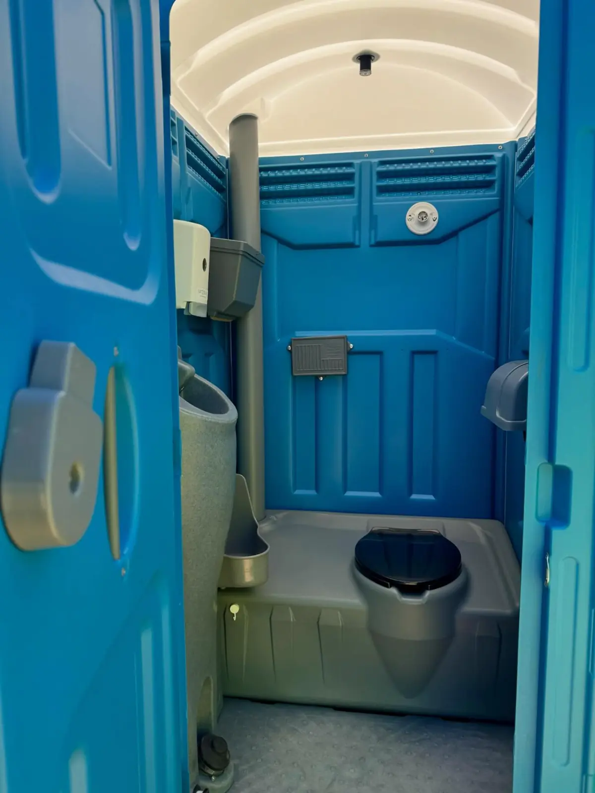 Inside a standard portable toilet: seat, toilet paper and sanitizer