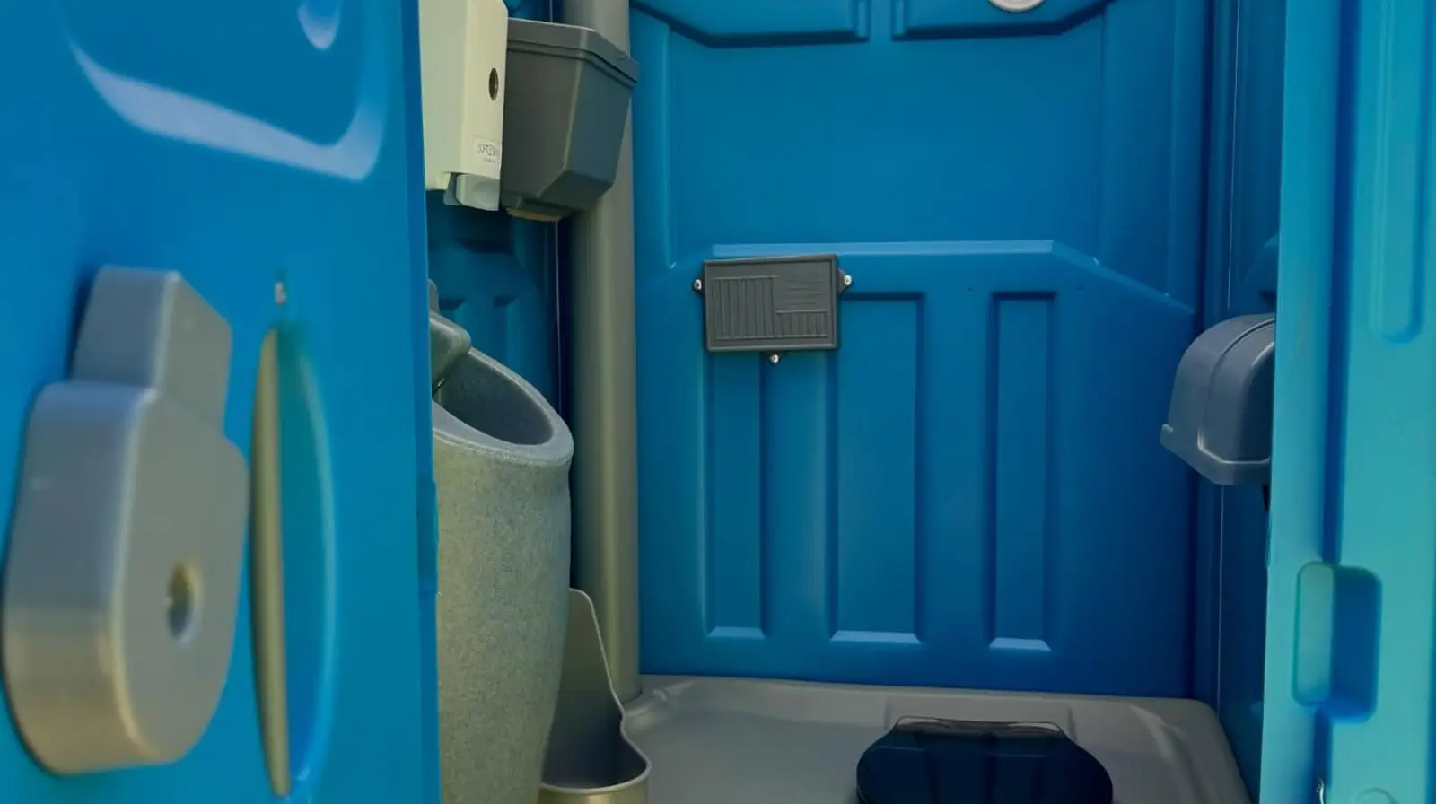 Inside a standard portable toilet: seat, toilet paper and sanitizer