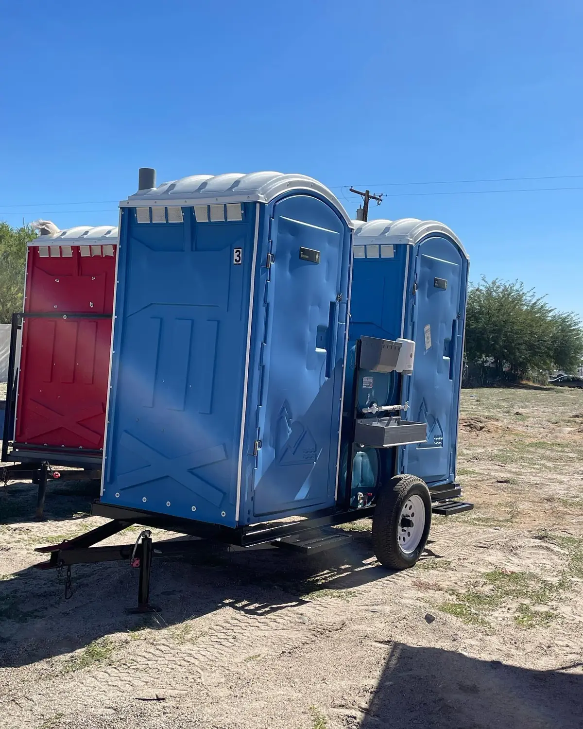 Blue towable portable toilet on a small trailer