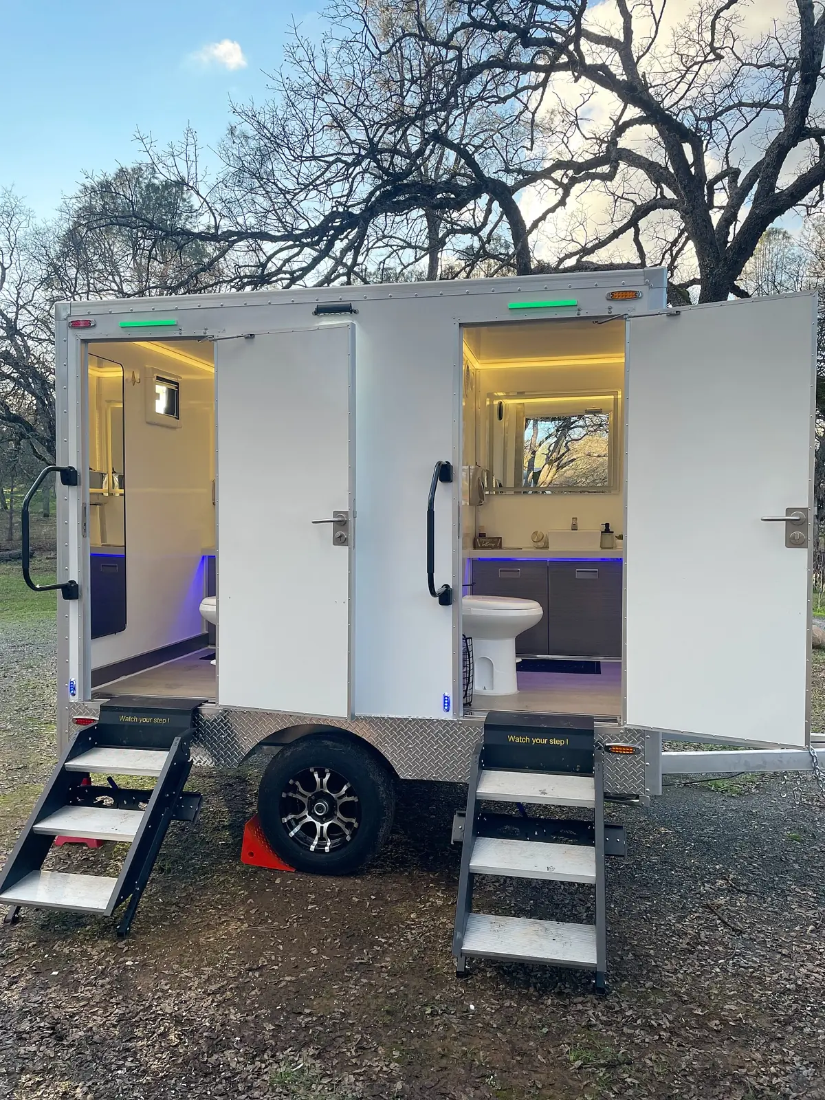 Two-stall restroom trailer with steps and lit interiors