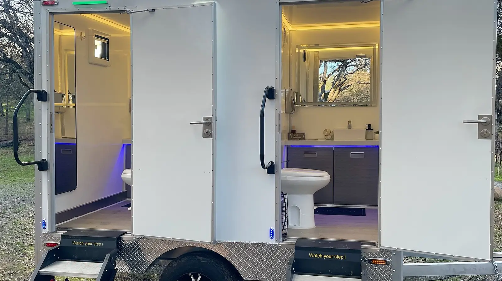 Two-stall restroom trailer with steps and lit interiors
